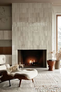 a living room with a fireplace, chair and ottoman in front of the fire place