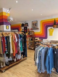 a clothing store filled with lots of colorful shirts and ties on display in front of a rainbow - striped wall