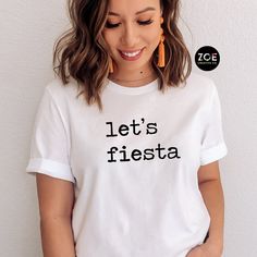 Lets Fiesta Shirt, Cinco De Mayo Fiesta Quote Shirt, Fiesta Tshirt, Funny Cinco De Mayo, Mexican Quote Shirt Mexican Celebration Theme Party This listing is for ( 1 ) Bella Canvas t-shirt of your choice in adult Unisex sizes.  To order MULTIPLES, add to cart one at a time. Available in the following colors: Berry, Pink, White, Heather Gray (light), Dark Gray, Yellow, Red, White, Natural, or Black WHITE lettering printed on: Dark Gray, Heather Gray, Berry, Black, Red, Green BLACK lettering printe Casual Crew Neck Tops For Festival, Graphic Tee With Letter Print For Festivals, Festival Graphic Tee With Letter Print, Casual Letter Print Tops For Festivals, Graphic Tee With Crew Neck For Festival, Casual Tops With Graphic Print For Festivals, Casual Graphic Print Tops For Festivals, Festival Cotton Crew Neck Top, Cotton Crew Neck Top For Festivals