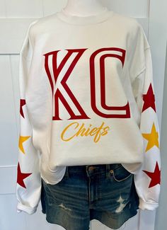 New Gildan white sweatshirt with KC Chiefs and star sleeve detail. Can crop at waist or hip length or keep regular band. This sweatshirt is designed and made by myself. More teams coming soon it reach out for custom team colors Kc Chiefs Sweater, Kc Royals Outfit Woman, Kansas City Chiefs Sweatshirts, White Team Spirit Streetwear Sweatshirt, White Team Spirit Sweatshirt For Streetwear, White Streetwear Team Spirit Sweatshirt, Customizable White Sweatshirt For Game Day, White Varsity Crew Hoodie, White Team Spirit Customizable Sweatshirt