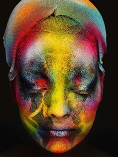 a woman's face is covered in multicolored powder and has her eyes closed