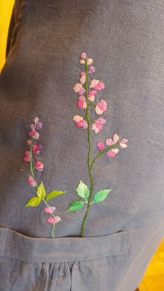 the back of a woman's pants with pink flowers embroidered on it and green leaves