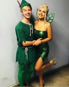 two people dressed as tinkerbells posing for a photo in front of a wall