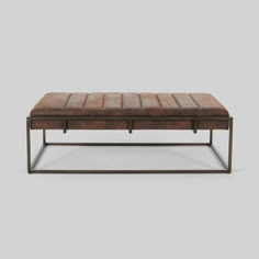 a brown leather bench with metal frame legs and foot rest on the bottom, in front of a gray background