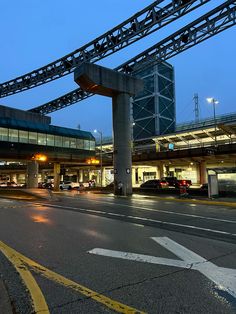 an airport terminal at night with cars parked on the street