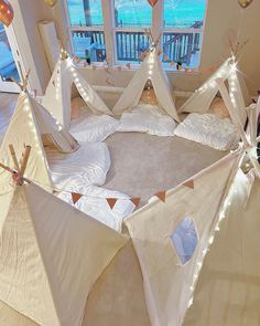 an indoor play area with teepees and lights on the ceiling, in front of a window