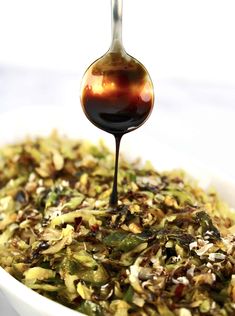 a spoon is pouring sauce into a bowl filled with vegetables and other foodstuffs