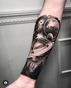 a man's arm with planets and trees on it