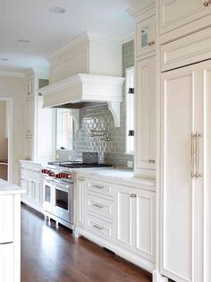 a large kitchen with white cabinets and wood floors