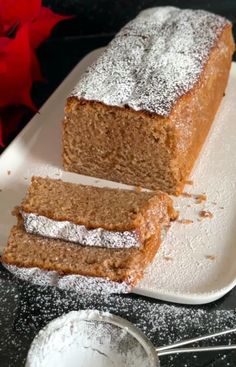 two slices of cake on a white plate with powdered sugar and spoons next to it