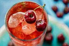 two cherries sit on top of ice in a glass with water and ice cubes