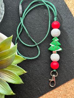 a green cord with red and white beads on it next to a potted plant