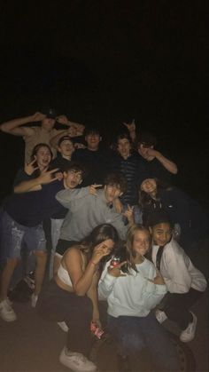 a group of young people posing for a photo at night with their arms around each other