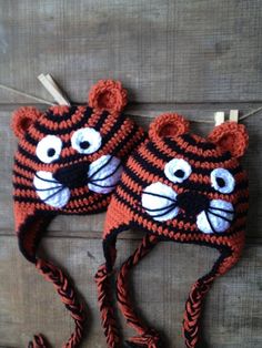 two crocheted tiger hats hanging from clothes pins