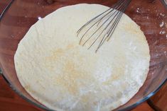 an uncooked pizza dough in a glass bowl with whisk on top