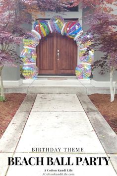 a birthday party with balloons and trees in front of the entrance to a house that is decorated