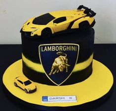 a cake with a lamb logo on it and a yellow car next to the cake