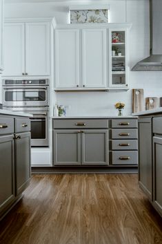 a kitchen with white cabinets and silver appliances in it's center island, along with hardwood flooring