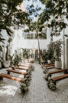 an empty courtyard with wooden benches and potted plants