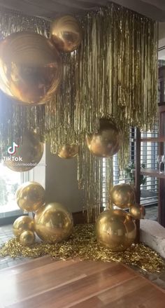 gold balloons are hanging from the ceiling in front of a wooden table and couches