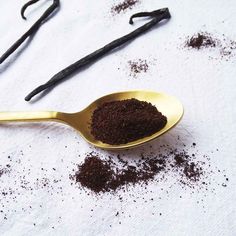 a spoon filled with brown stuff next to vanilla sticks