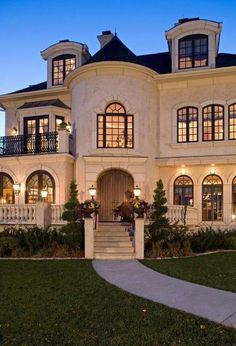 a large white house with lots of windows and lights on it's front porch