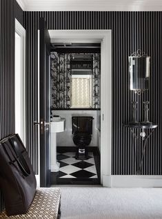 a black and white bathroom with a checkered floor, wallpapered walls and a toilet in the corner