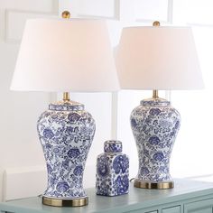 two blue and white vases sitting on top of a table next to a lamp