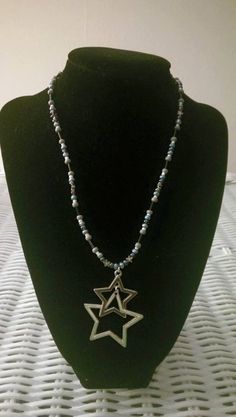 "This one-of-a-kind beaded necklace is made with small metal star beads, blue, purple, white, and black seed beads, and a metal star pendant dangling in the middle. Toggle clasp. Measures 16\" long end to end." Purple Star Necklace, Black Seed, Metal Stars, Black Necklace, Star Pendant, Silver Stars, Star Necklace, Purple And Black, Seed Beads