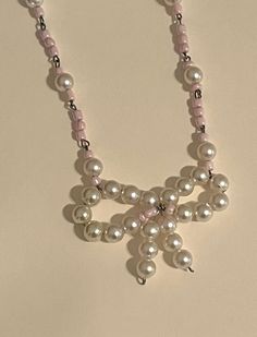 a pink necklace with white pearls and silver beads on a light colored background is shown