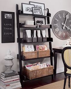 a room with a desk, bookshelf and clock on the wall above it