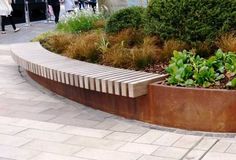 a large metal planter sitting on top of a sidewalk next to a park bench