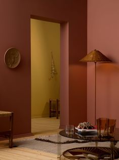 a living room filled with furniture and a lamp on top of a coffee table in front of a pink wall