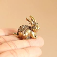 a small gold rabbit figurine sitting on top of someone's hand