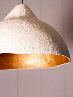 a white and gold colored light hanging from a ceiling