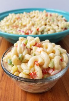 macaroni salad in a glass bowl on a wooden table with the words creamy cheese macaroni salad