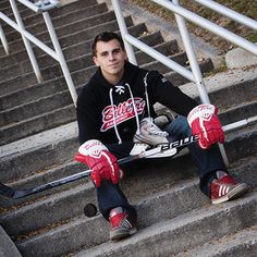 a young man sitting on the steps with his hockey gloves and skateboard in front of him