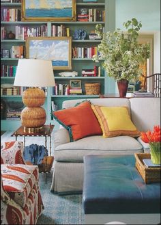 a living room filled with lots of furniture and bookshelves covered in colorful books