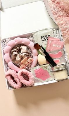 an open box containing makeup and accessories on a pink surface with a white fur rug