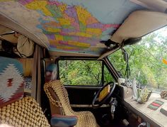 the interior of an old bus is decorated with colorful maps and wicker furniture,