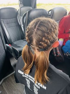 a woman sitting in the back seat of a car with her hair in a pony tail braid