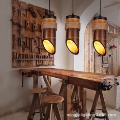 three lights hanging over a wooden table with stools in front of it and wood work on the wall behind them