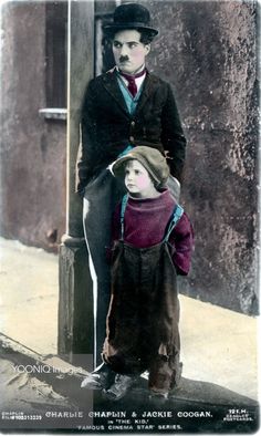 an old photo of two children standing next to each other on the sidewalk, wearing hats and scarves