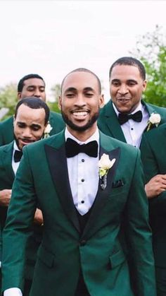 a group of men in green tuxedos standing next to each other and smiling