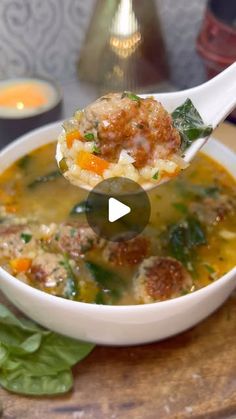 a spoon full of soup with meatballs and spinach