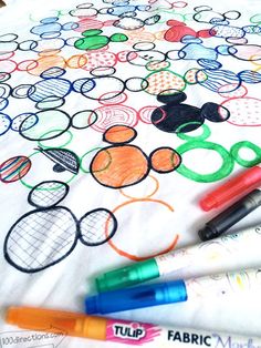 some markers are laying on top of a t - shirt with mickey mouses and tennis balls