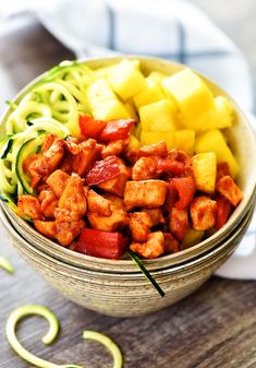 a bowl filled with meat and veggies on top of a wooden table next to sliced zucchini