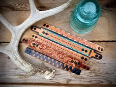 four different types of hair combs sitting on top of a wooden table next to a deer's antler