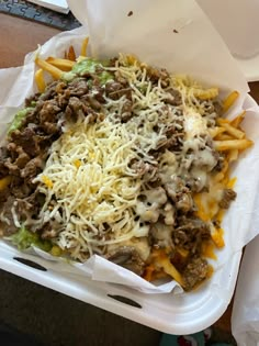 a plastic container filled with french fries covered in cheese and ground beef toppings on top