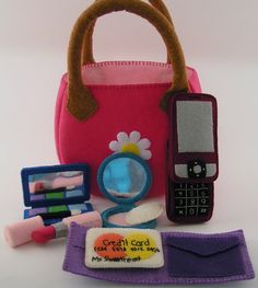 a cell phone, wallet, and other items are on a white surface with a pink handbag in the background